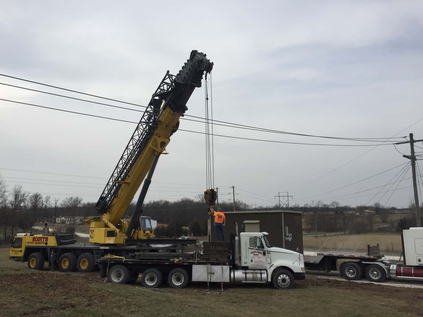 A crane lifting a power hub off of a flatbed truck.