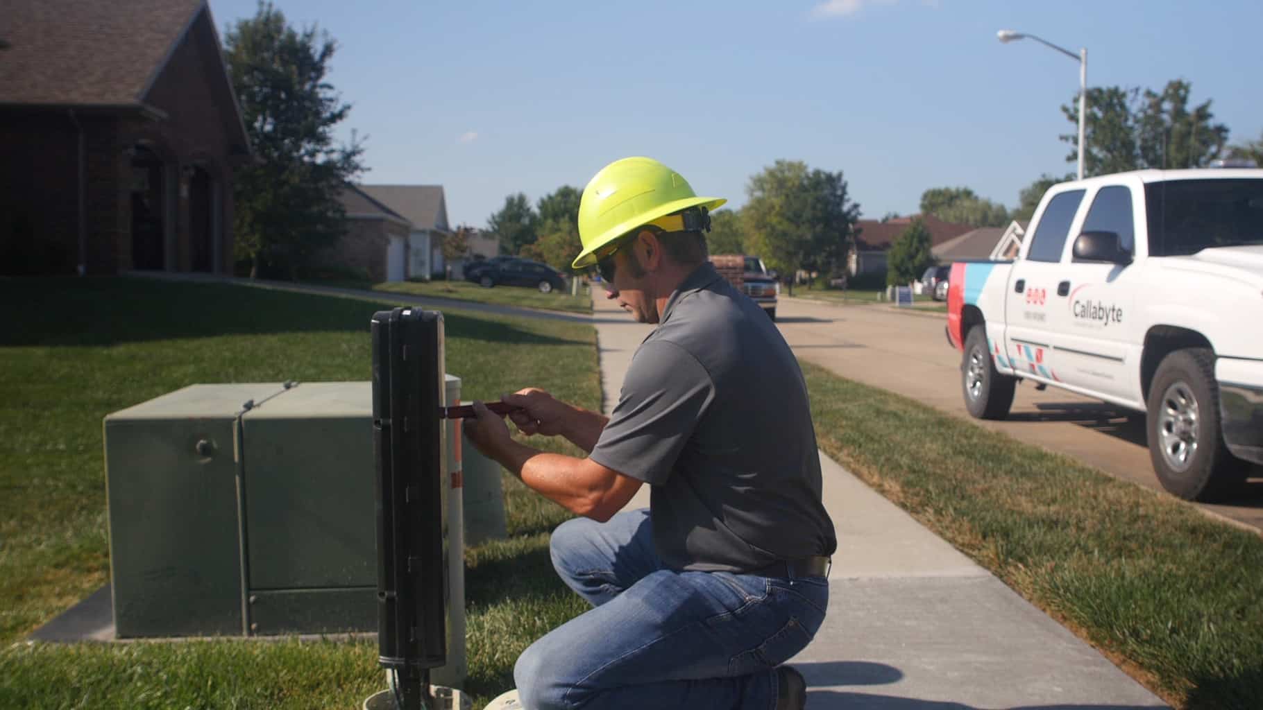 Technician working on a cable box outside a home.