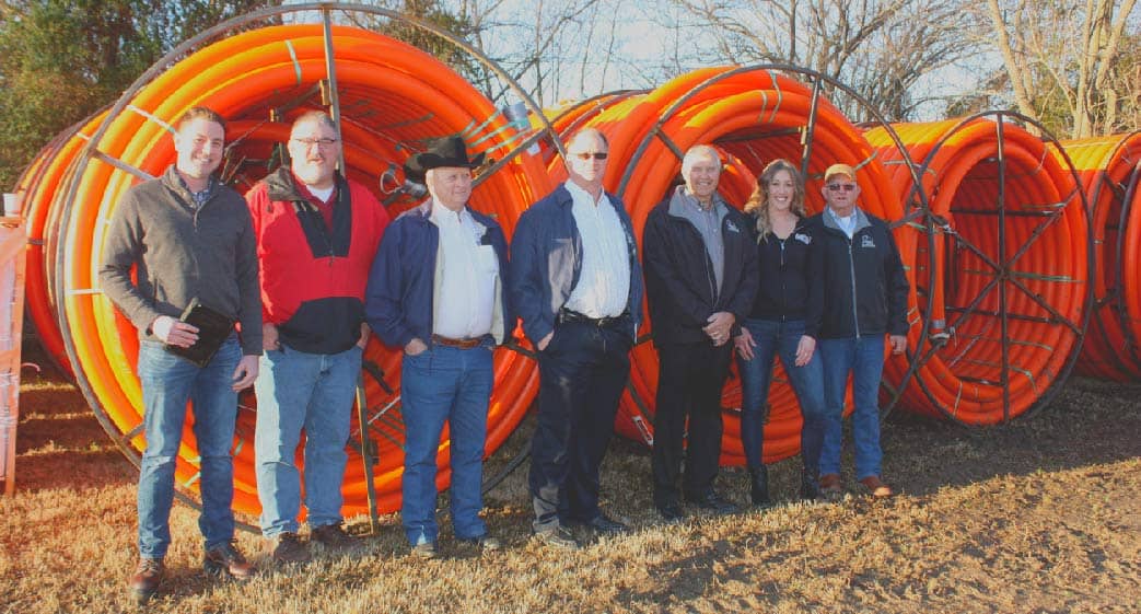 Ecolink leaders stand in front of big fiber cable wheels.