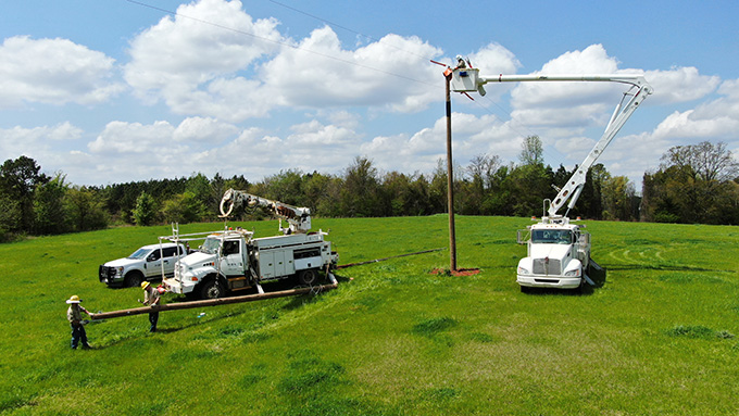 Multiple lift trucks in a farm field working on power poles.