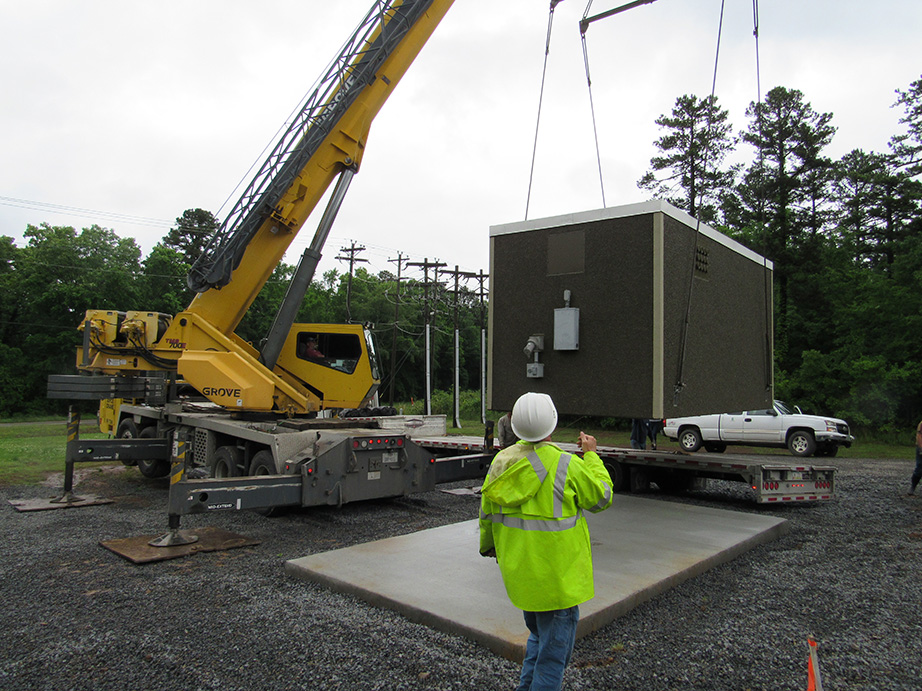 Crane lifting a fiber hut to the ground.