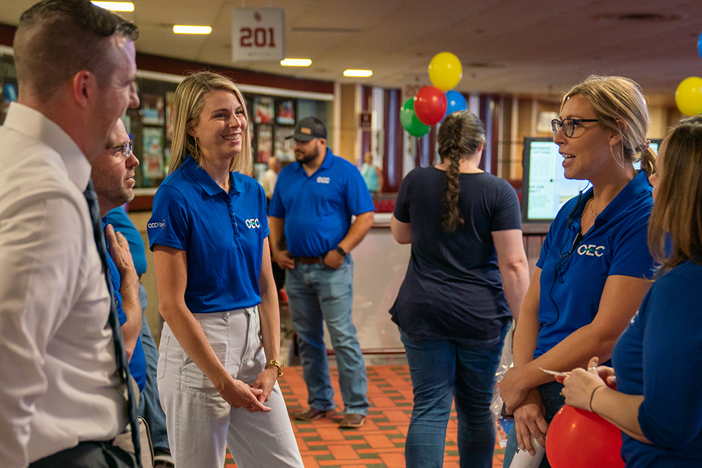 OEC employees smiling and talking in a group.