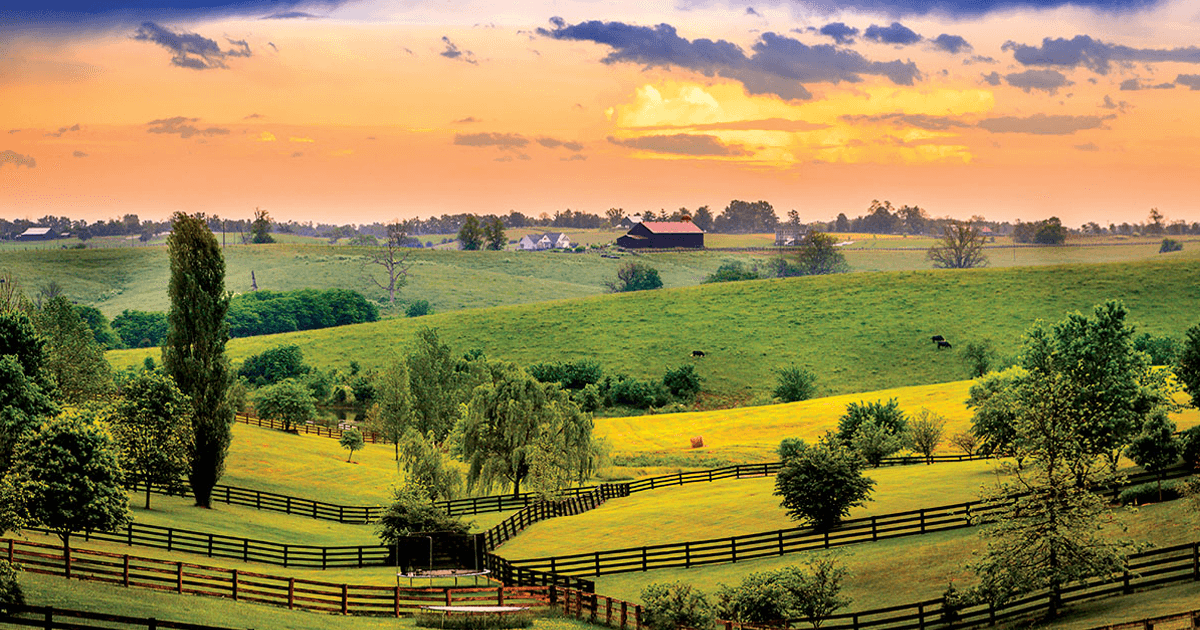 Hilly farm pastures with barns in the background during a sunset.