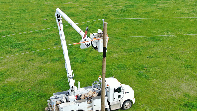 An arial shot of a lift truck hoisting a electrician to work on the cables.