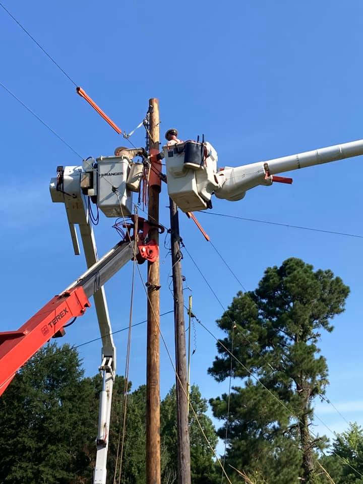 Cherry picker hoisting electrician to work on power poles.