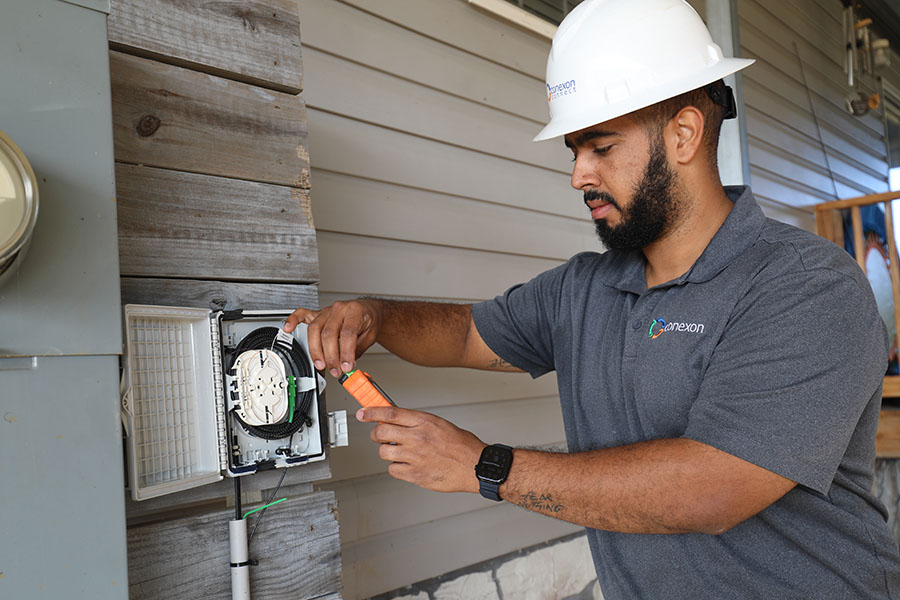 Man wearing a hard hat assesses a terminal outside a home.